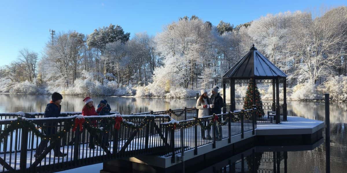 Families enjoying a snowy dock decorated for waterfront holiday gatherings beside calm winter water.